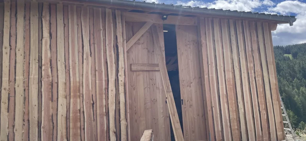Bardage vertical en planches à bords bruts sur un bâtiment de montagne, en fin de chantier