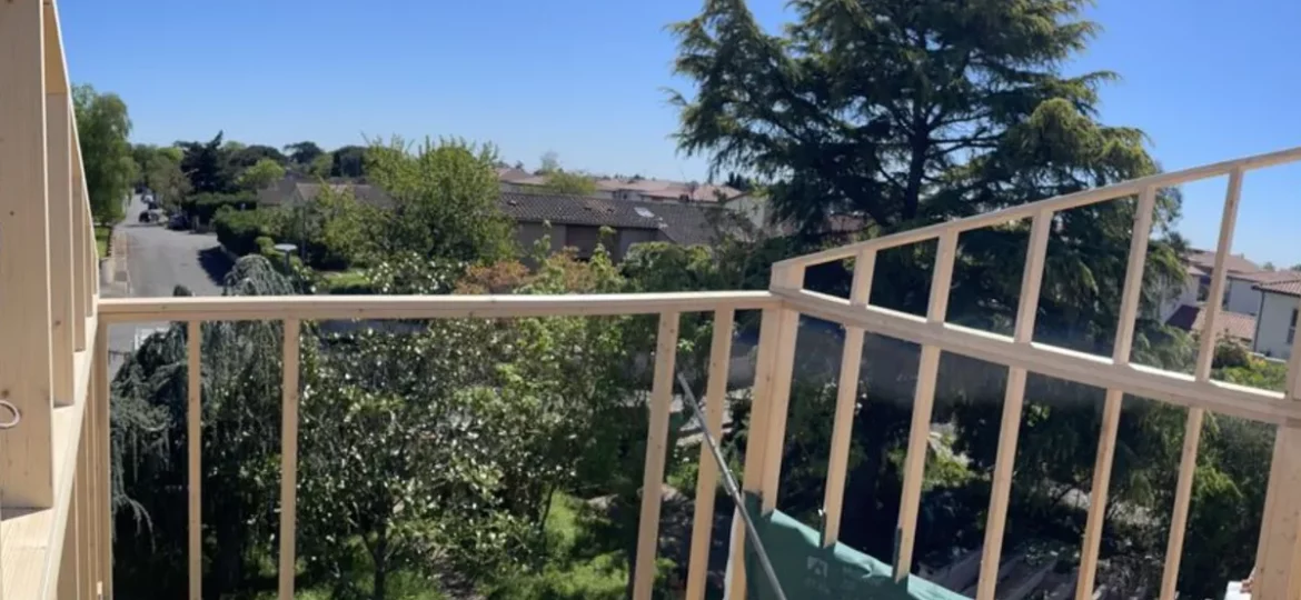 Chantier d’ossature bois en hauteur, au-dessus des jardins d’un quartier résidentiel